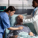 African doctor and medical assistant helping senior man breath